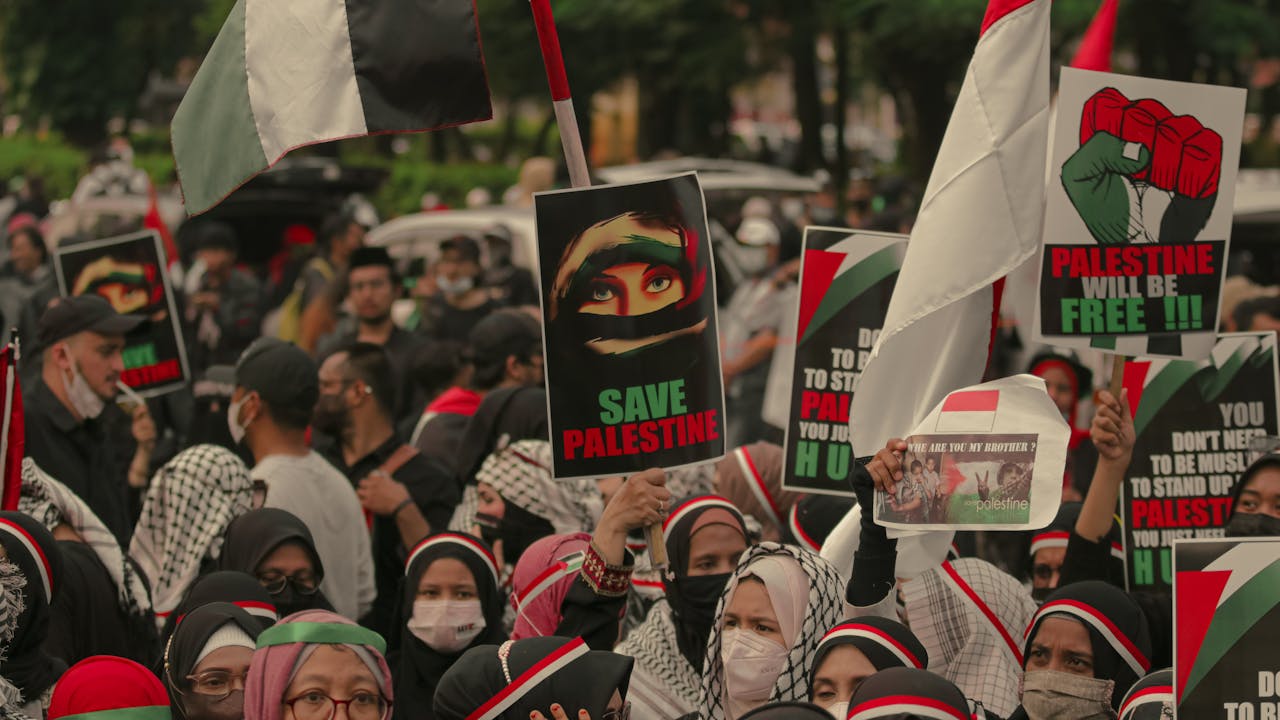 A large protest in Jakarta advocating for Palestinian freedom with signs and flags.
