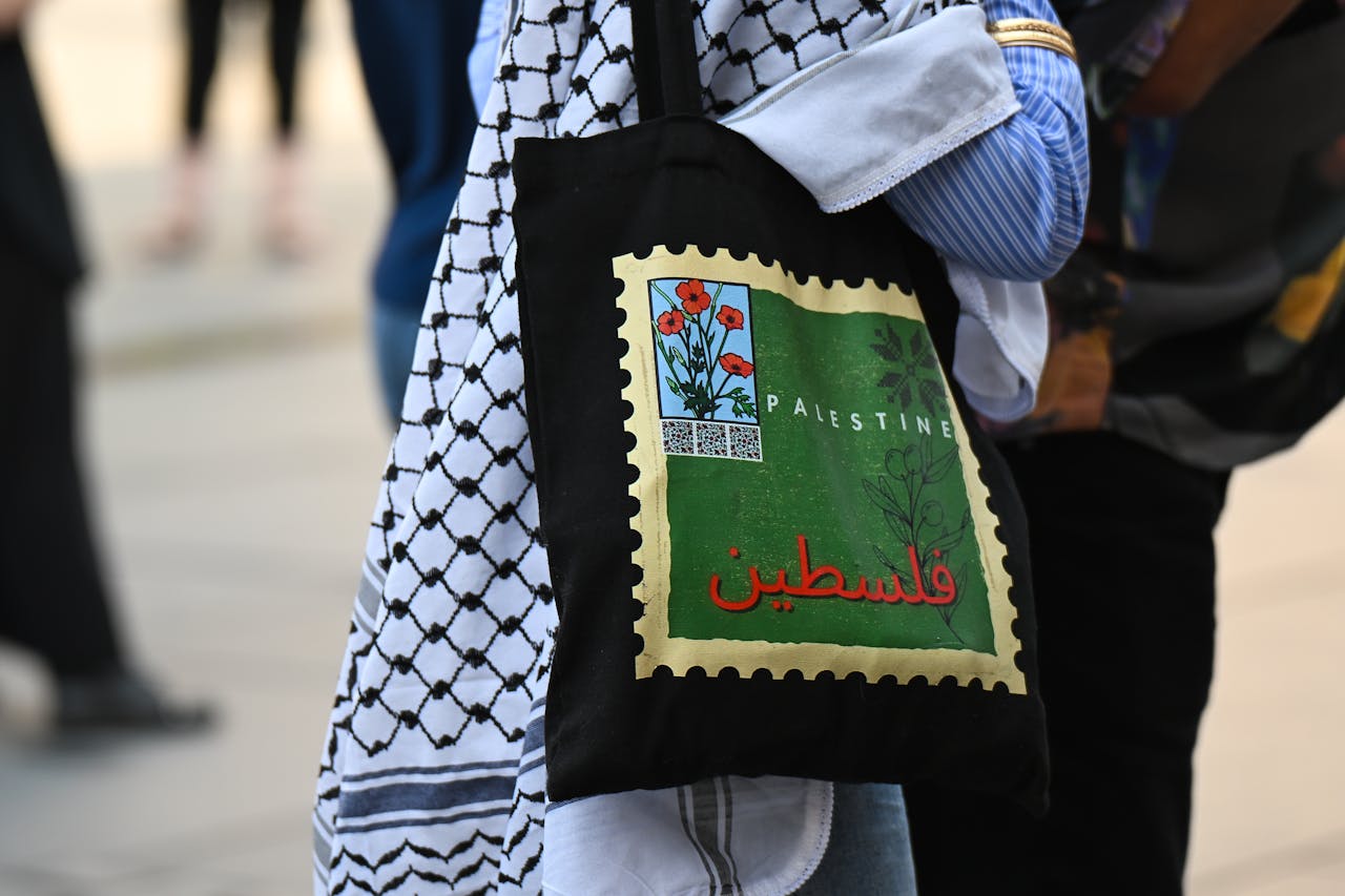 A close-up of a bag featuring Palestinian imagery during a street protest.
